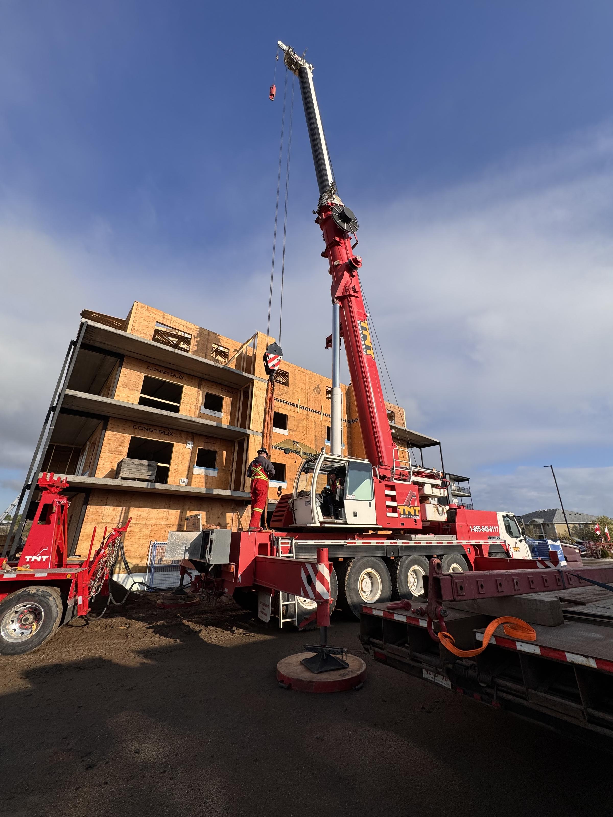 Crane setting framing components on a multifamily site